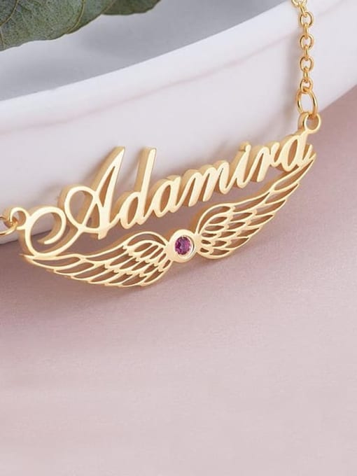 Gold necklace with 'Adamira' and a red gemstone on a light pink background